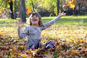 little girl play with autumn leaves