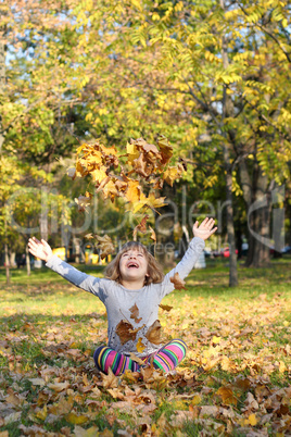 little girl throws autumn leaves