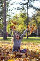 happy little girl throws leaves