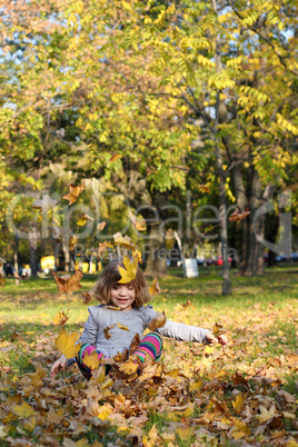 little girl play with autumn leaves