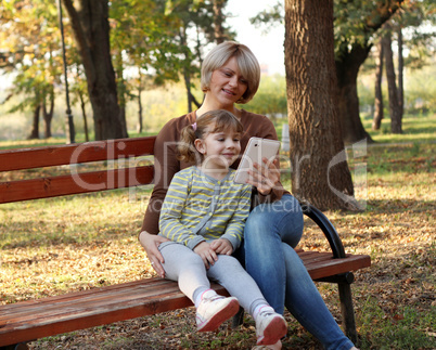 mother and daughter with tablet in park