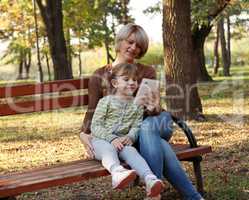 mother and daughter with tablet in park