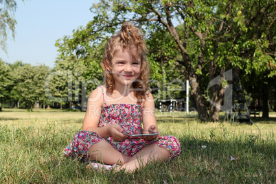 little girl with tablet pc in park