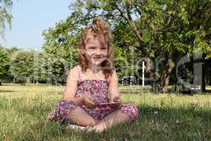little girl with tablet pc in park