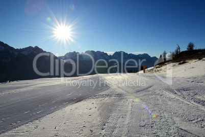 The ski slope with a view on Dolomiti mountains and sun, Madonna