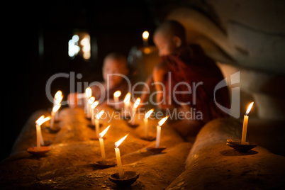 Buddhist novices with candle light inside temple
