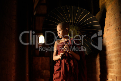 Buddhist novice walking with umbrella