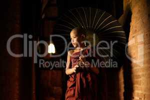 Buddhist novice walking with umbrella