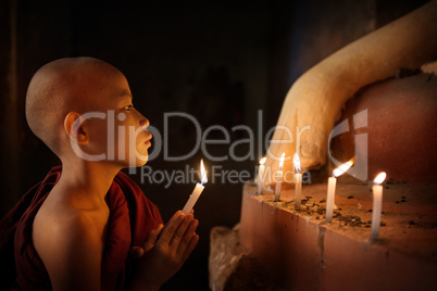 Buddhist novices praying with candlelight in temple