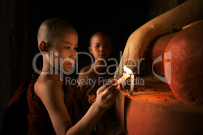 Buddhist novices praying with candlelight in monastery