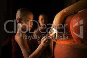 Buddhist novices praying with candlelight in monastery