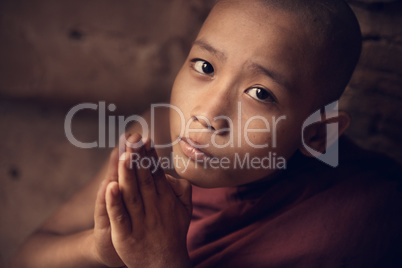 Buddhist novice monk praying in monastery