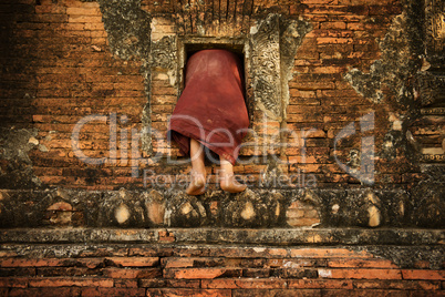 Buddhist novice monk climbing into monastery