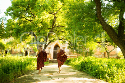 Young Buddhist novice monks running outside monastery