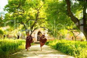 Young Buddhist novice monks running outside monastery