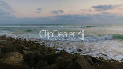 Sunset at Sea. Waves and foam on rocky beach Indian Ocean.