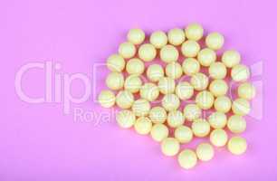 yellow vitamins on pink background