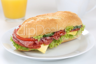 Sandwich Baguette belegt mit Salami zum Frühstück mit Orangens
