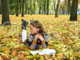 young girl reads a book in the autumn park
