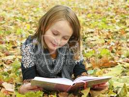 teen reads a book in the autumn park