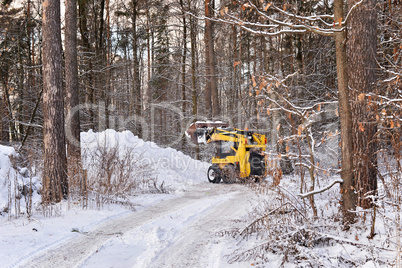 The tractor clears snow from the road