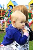 Mother carries her daughter in the playground