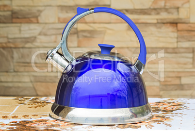 Bright blue kettle on the tablecloth table.