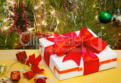 Beautifully packed gift by Christmas and the decorated fir-tree.