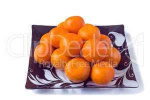 Large ripe tangerines in a glass dish on a white background.