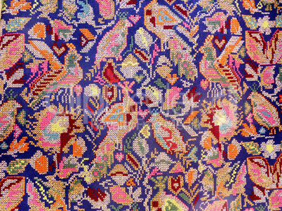 Close up of handmade embroidered fabric with motifs of birds