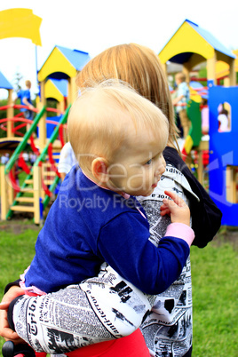 Mother carries her daughter in the playground