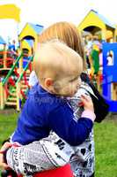 Mother carries her daughter in the playground