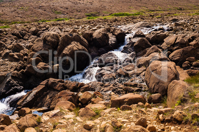 Stream flowing and splashing among bare rocky landscape