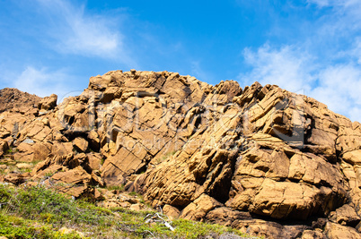 Large irregular cracked rock outcrop against sky