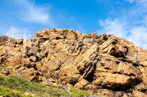 Large irregular cracked rock outcrop against sky