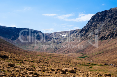 Dry rocky valley between cliffs under pale blue sky