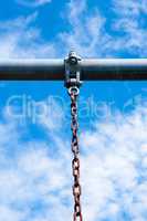 Metal bar with rusted chain hanging against sky