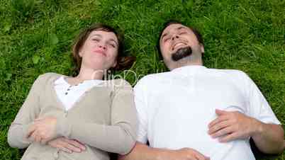middle aged couple in love lying in grass and talk