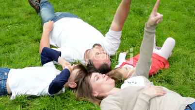 family (middle aged couple in love, boy and girl) lying in grass and talk