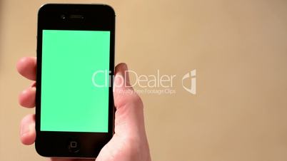 Hand (young man) holds a smartphone - green screen