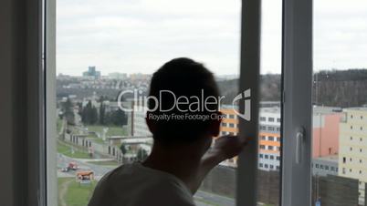 Man opens and closes the window - street with cars in background (medium close-up)
