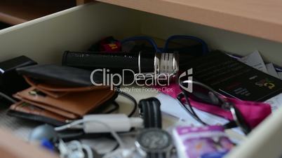 Hand opens and closes the drawer with different things (close up)