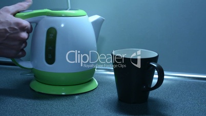 Switching on the kettle with cup on the kitchen counter