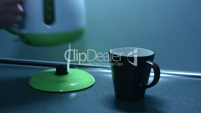 Switching on the kettle and Insert a tea bag into a cup to on the kitchen counter