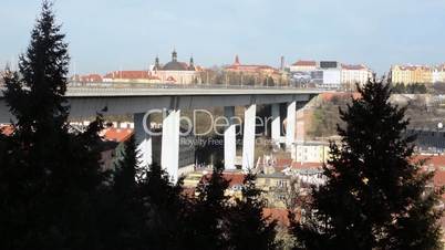 Cars drive on the Nusle Bridge, city in the background