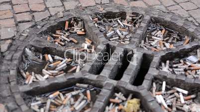 Cigarette butts on the street at the top of the sewer
