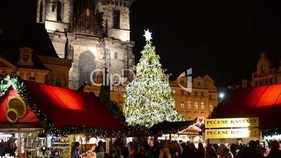 Shining Christmas Tree with Christmas shops with people - on Old Town Square. In background historical building.