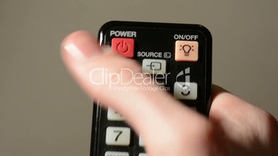 hand (young man) presses a button on the remote control to turn off