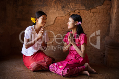 Two young Myanmar girls praying in temple