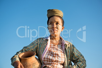 Mature Asian traditional female farmer carrying clay pot